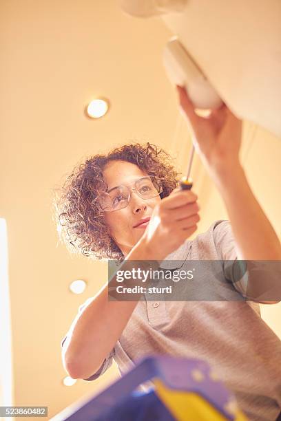 female alarm contractor - installing ceiling light fixture stock pictures, royalty-free photos & images