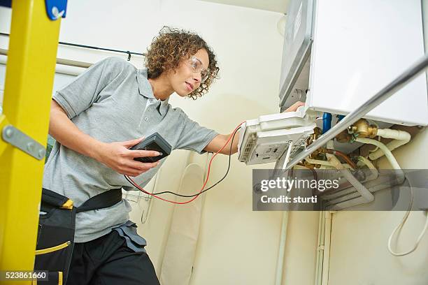female plumber servicing a boiler - installing ceiling light fixture stock pictures, royalty-free photos & images