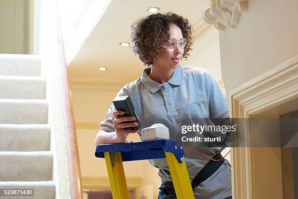 female electrician testing alarm sensor - installing ceiling light fixture stock pictures, royalty-free photos & images