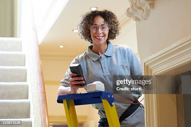 female electrician testing alarm sensor - installing ceiling light fixture stock pictures, royalty-free photos & images