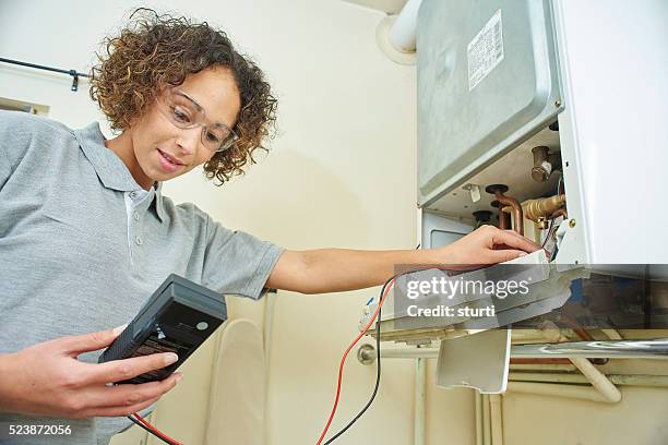 female plumber electrically testing a boiler - installing ceiling light fixture stock pictures, royalty-free photos & images