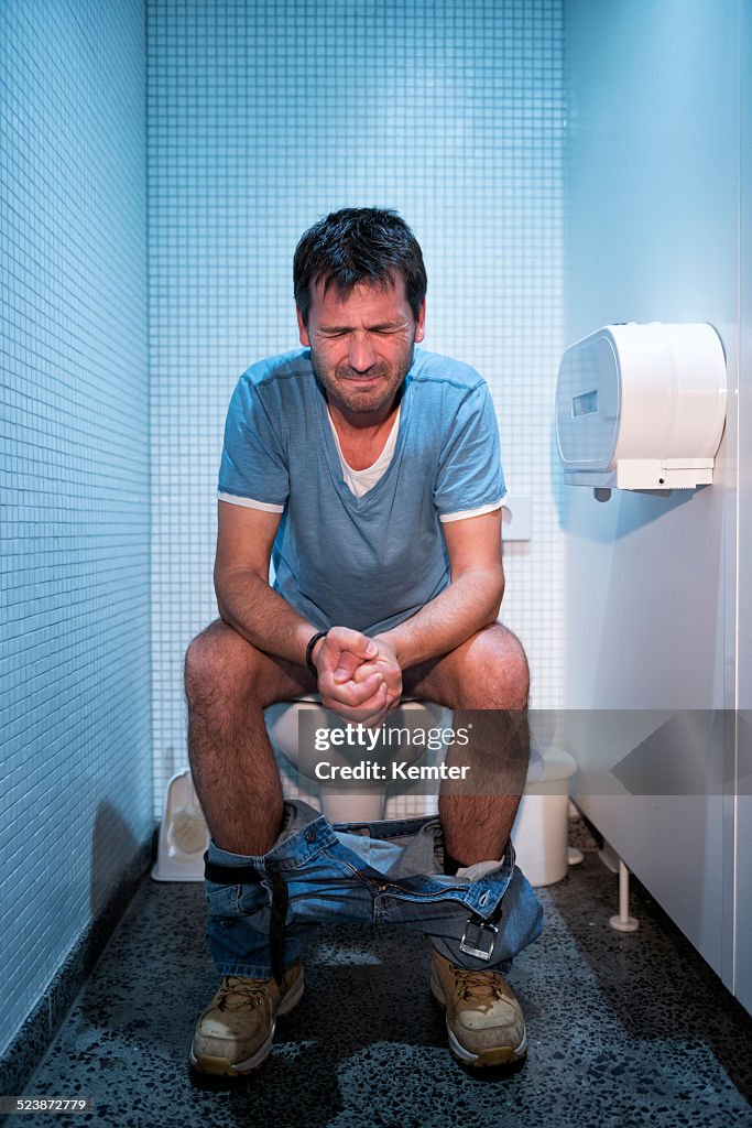 Man sitting in public restroom
