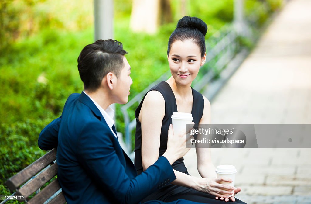 Dois jovens asiáticos adultos beber café durante a data no parque