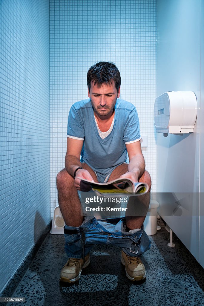 Man sitting in public restroom