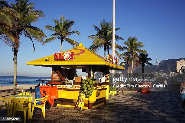 The early morning light catches a beachside refreshment kiosk which includes fresh coconuts, Ipanema beach. Rio de Janeiro, Brazil. 12th July 2010....