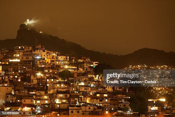 View from Santa Teresa in the hills of Rio de Janeiro as The iconic Cristo Redentor, Christ the Redeemer statue appears out of the clouds while lit...