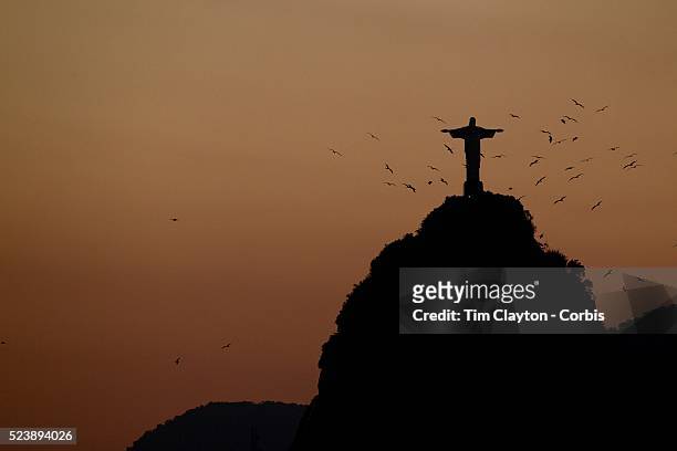 The iconic Cristo Redentor, Christ the Redeemer statue at sunset atop the mountain Corcovado shot from Sugar Loaf Mountain. The Christ statue was...