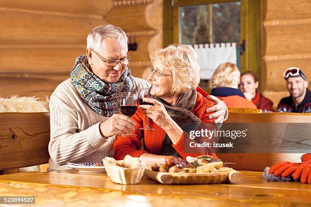 senior couple having lunch after skiing, toasting wiht wine - cosy pub stock pictures, royalty-free photos & images