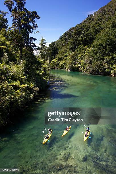 Kayakers venture down crystal clear waters of a sheltered lagoon in the Abel Tasman National Park., South Island, New Zealand, The Abel Tasman...