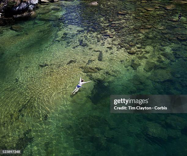 Kayaker takes a break and enjoys a swim in the crystal clear waters of a sheltered lagoon in the Abel Tasman National Park., South Island, New...