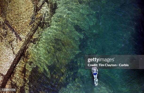 Kayaker takes a break and enjoys a swim in the crystal clear waters of a sheltered lagoon in the Abel Tasman National Park., South Island, New...