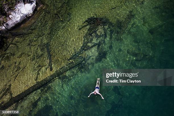 Kayaker takes a break and enjoys a swim in the crystal clear waters of a sheltered lagoon in the Abel Tasman National Park., South Island, New...
