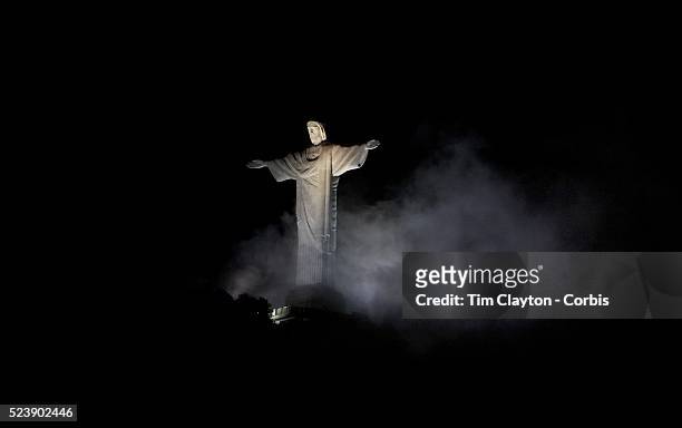 The iconic Cristo Redentor, Christ the Redeemer statue appears out of the clouds while lit up at night time atop the mountain Corcovado. The Christ...