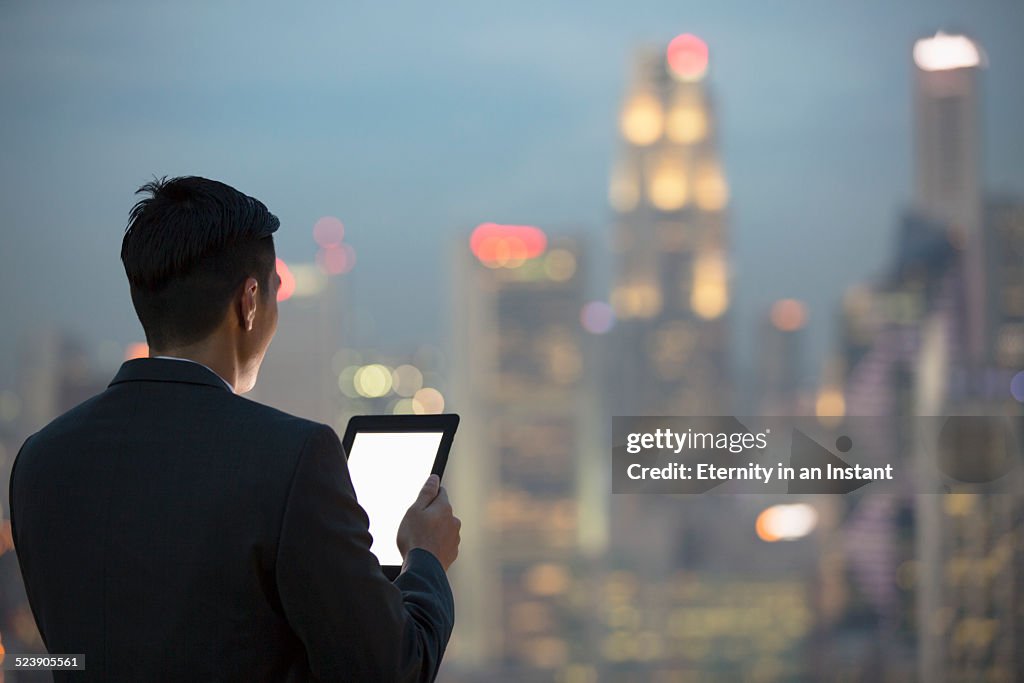 Businessman with digital tablet looking at city