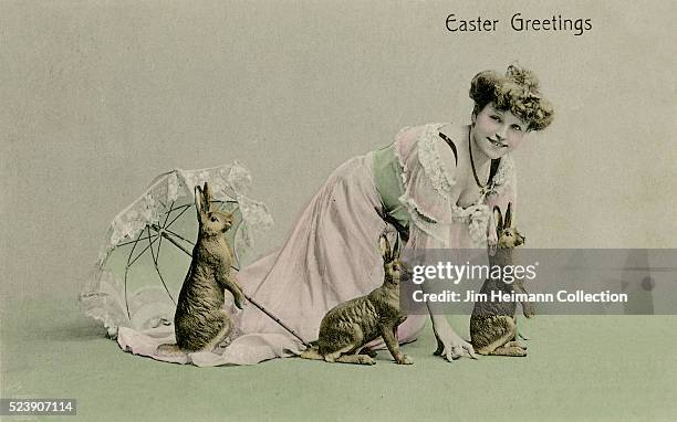 Easter postcard featuring photograph of young woman with three rabbits and parasol.