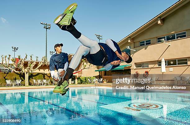 Bob Bryan and Mike Bryan of the United States dive in the swimming pool after defeating Marcel Granollers of Spain and Pablo Cuevas of Uruguay in the...