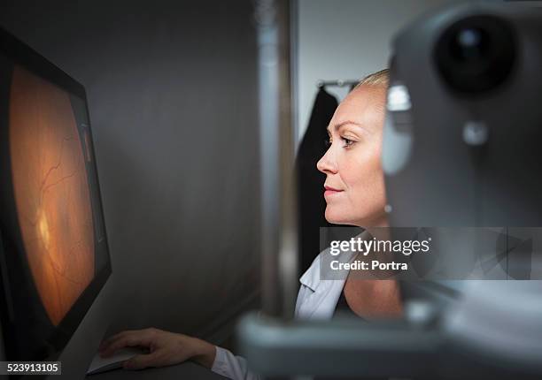 optometrist examining retina on computer - retina stock pictures, royalty-free photos & images