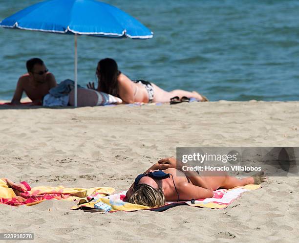 Tourist uses the top of her bikini to protect her face from the sun while sunbathing topless at the beach in Canet-en-Roussillon, France, 05...