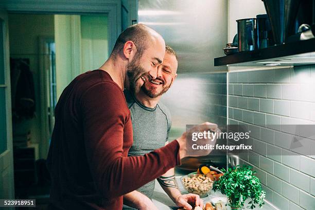 gay couple, préparer un repas dans la cuisine - man cooking photos et images de collection