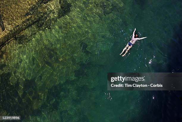 Kayaker takes a break and enjoys a swim in the crystal clear waters of a sheltered lagoon in the Abel Tasman National Park., South Island, New...