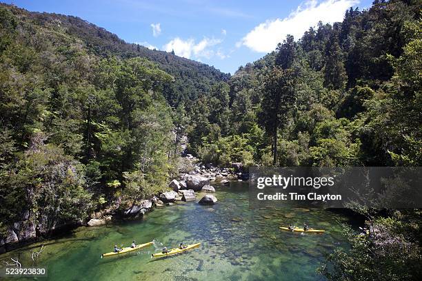 Kayakers venture down crystal clear waters of a sheltered lagoon in the Abel Tasman National Park., South Island, New Zealand, The Abel Tasman...