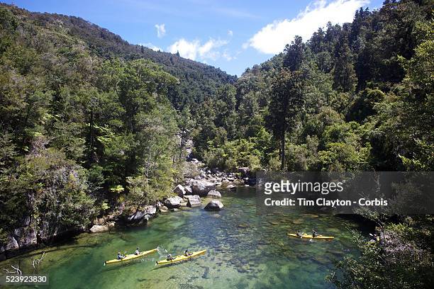 Kayakers venture down crystal clear waters of a sheltered lagoon in the Abel Tasman National Park., South Island, New Zealand, The Abel Tasman...