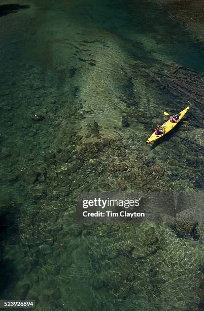 Kayakers venture down crystal clear waters of a sheltered lagoon in the Abel Tasman National Park., South Island, New Zealand, The Abel Tasman...