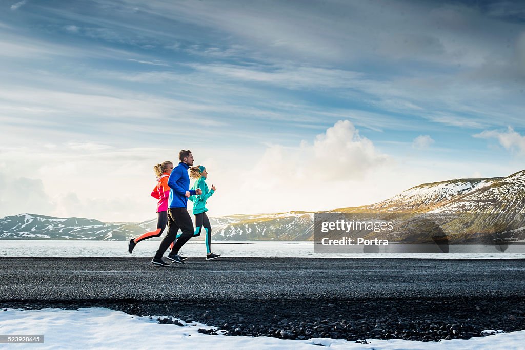 Friends running on road during winter