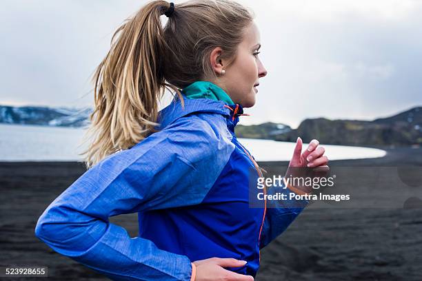 determined woman running at lakeside - sportswear stock pictures, royalty-free photos & images