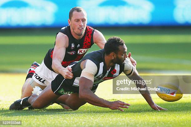 Travis Varcoe of the Magpies taps the ball away from James Kelly of the Bombers during the round five AFL match between the Collingwood Magpies and...