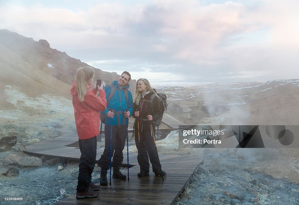 Hiker photographing friends on volcanic landscape
