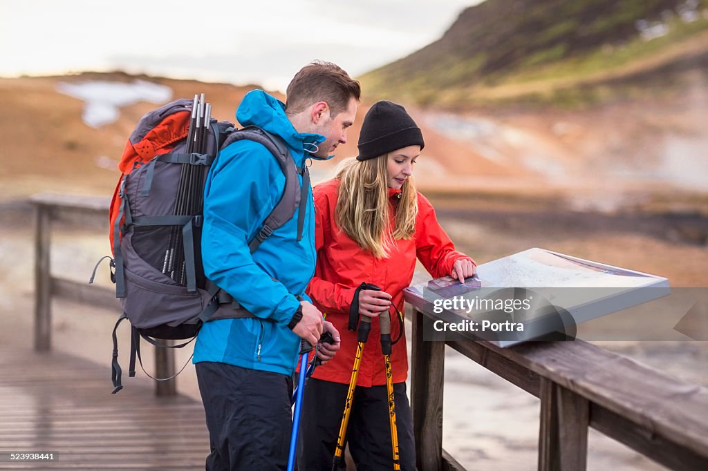 Hiking couple reading map at volcanic landscape