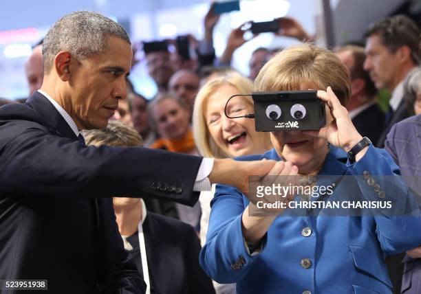 German chancellor Angela Merkel looks through a device next to US President Barack Obama at the booth of German automation company ifm electronic as...
