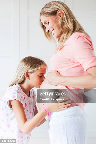 tochter und schwangere mutter glücklich mit spannung - belly kissing stock-fotos und bilder