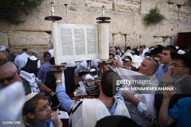 Jewish men, draped in prayer shawls, lift the Torah as they take part in the Cohanim prayer during the Pesach holiday at the Western Wall in the Old...