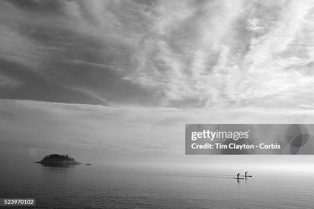 Tranquil scene in Madison, Connecticut as two paddle boarders enjoy Christmas day as they paddle on calm waters while a heat mist rises from the sea....