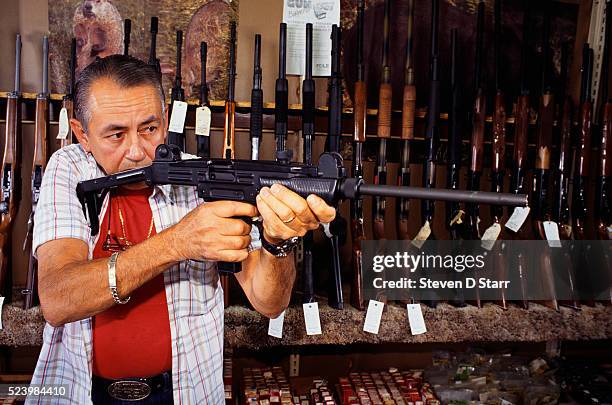 Gun shop employee Ramon Sanchez aims a nonautomatic uzi, which is legal for counter sale without a permit in Miami.