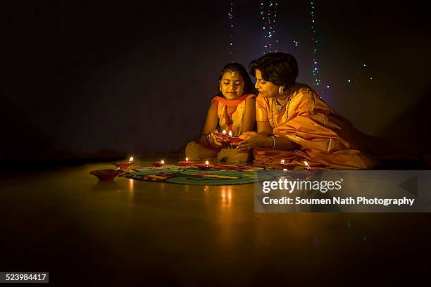 mother and daughter with diyas on diwali - diwali stock pictures, royalty-free photos & images