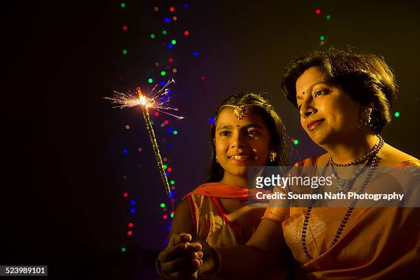 mother and daughter holding a sparkler on diwali - soumen nath stock pictures, royalty-free photos & images