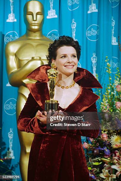 Juliette Binoche holds the Best Supporting Actress Oscar she won for her role in The English Patient.