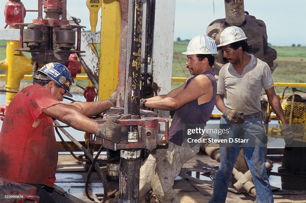 Three roughnecks work on an oil drilling rig in the middle of Lake ...