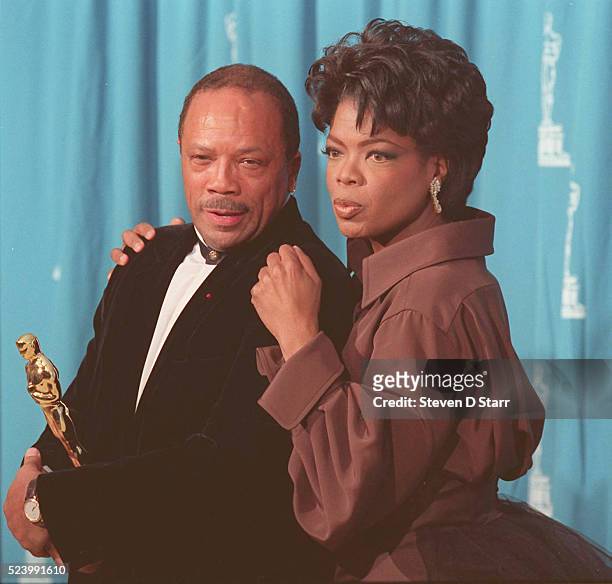 Quincy Jones is joined by Oprah Winfrey at the 1995 Academy Awards ceremony in Los Angeles. Jones was awarded the Jean Hersholt Humanitarian Award,...