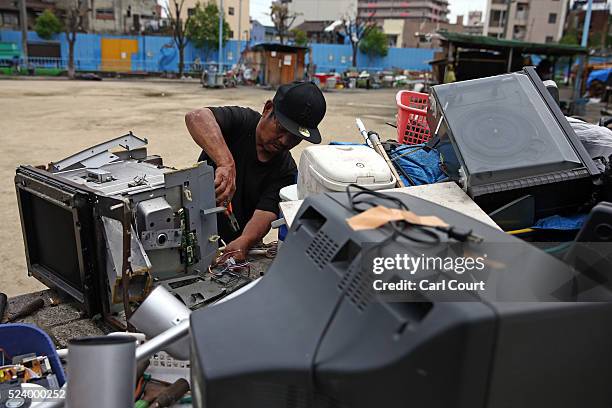 Man dismantles a television to sell the parts, in the slum area of Kamagasaki on April 23, 2016 in Osaka, Japan. Kamagasaki, a district in Japan's...