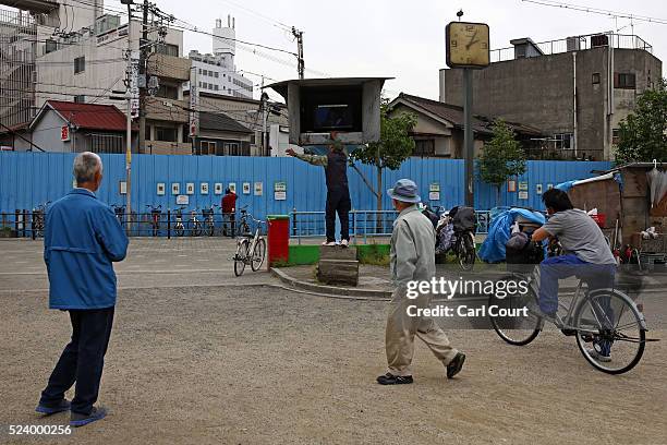 Men watch a television supplied by the local government in the slum area of Kamagasaki on April 24, 2016 in Osaka, Japan. Kamagasaki, a district in...