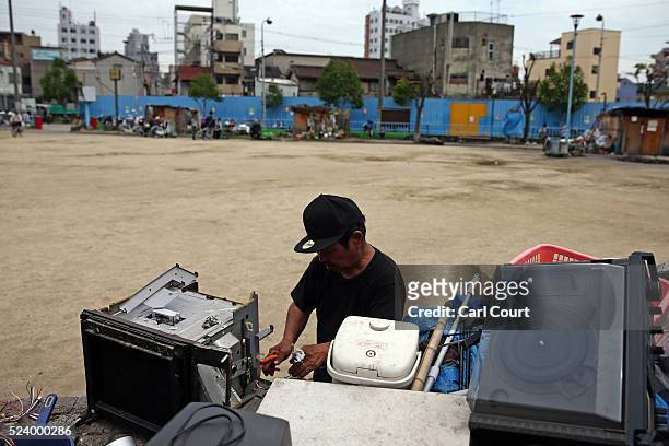 Man dismantles a television to sell the parts, in the slum area of Kamagasaki on April 23, 2016 in Osaka, Japan. Kamagasaki, a district in Japan's...
