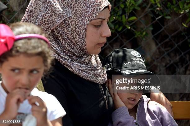 Child looks on as Queen Rania of Jordan speaks to the press during her visit at the refugee site of Kara Tepe in Mytilene on April 25, 2016. / AFP /...