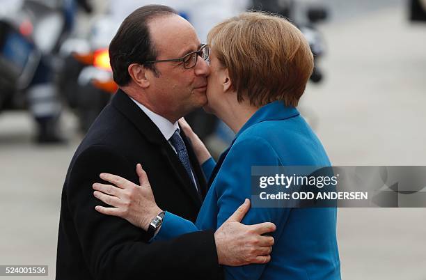 German Chancellor Angela Merkel kisses French President Francois Hollande as he arrives for an informal meeting at the Herrenhausen Palace in...