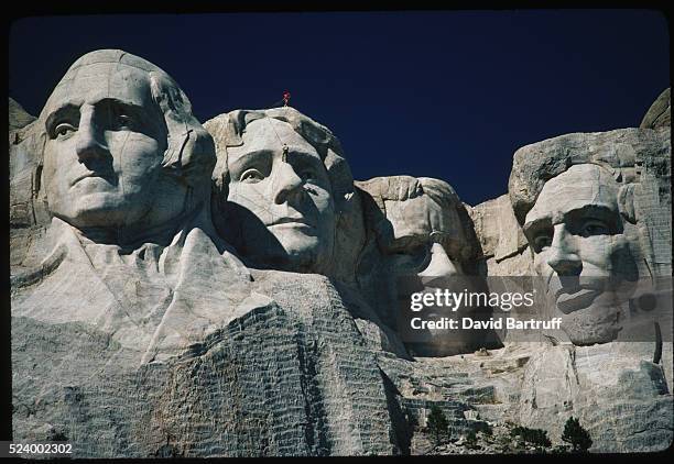 Workers scale the faces of Mount Rushmore while doing annual maintenance work on the four US presidents. Left to right they are George Washington,...