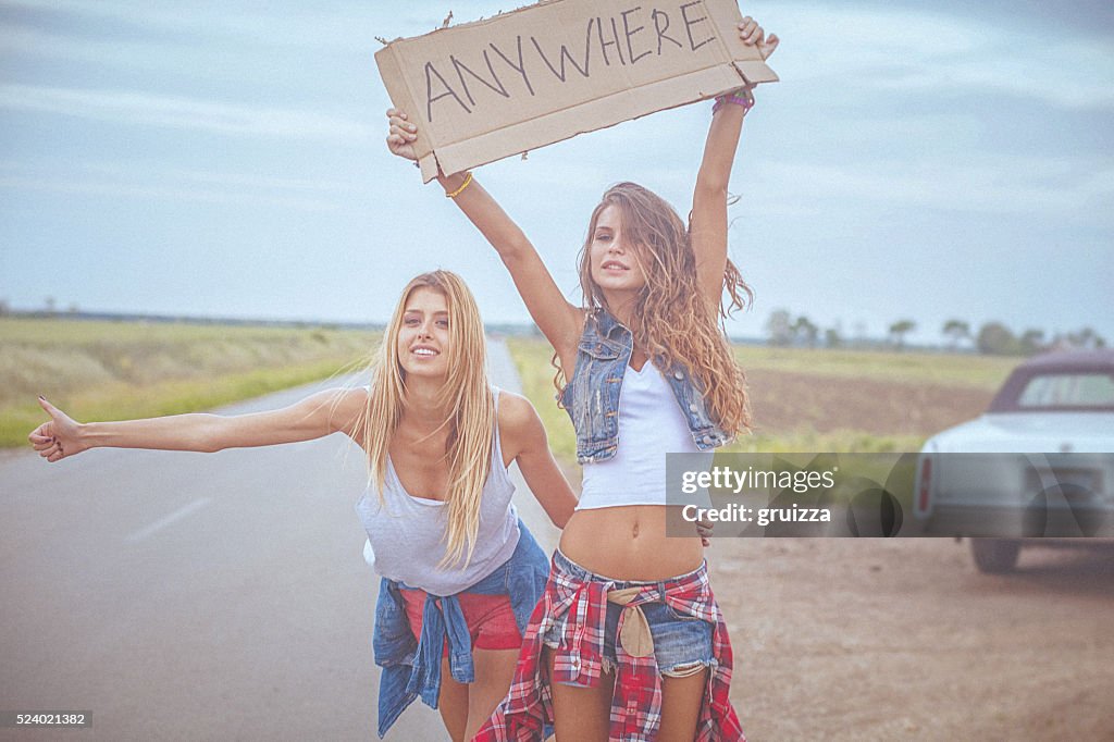 Zwei wunderschöne fröhlich hipster Freunde Trampen an der road