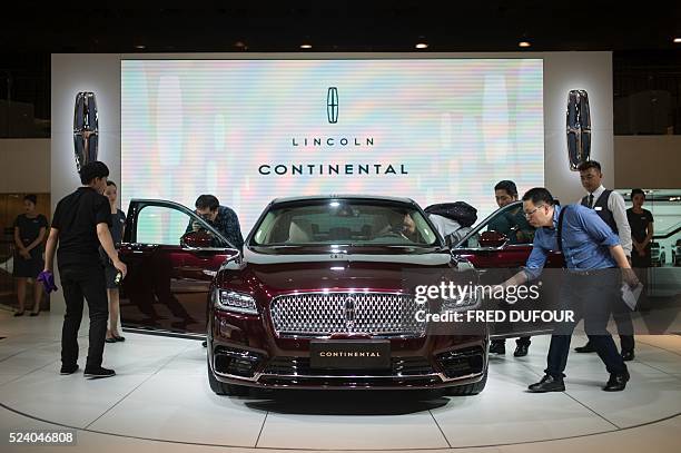 Chinese guests and journalists look at a Lincoln Continental on display at the Beijing Auto Show in Beijing on April 25, 2016. Global carmakers...